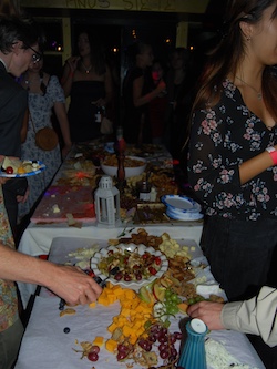 Tables covered with finger food, people partying